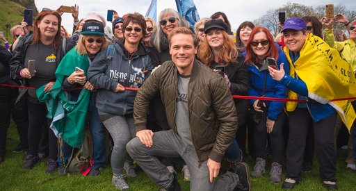 Sam Heughan, President Blood Cancer UK Scotland, poses for a photo in front of a group of My Peak Challenge participants.