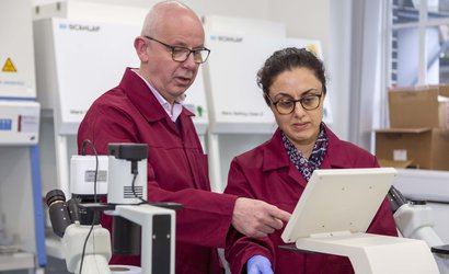 Two researchers stand in a laboratory. They are examining the screen of a piece of equipment.