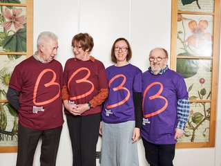 Group of Blood Cancer UK supporters standing side-by-side smiling together wearing Blood Cancer UK branded t-shirts.