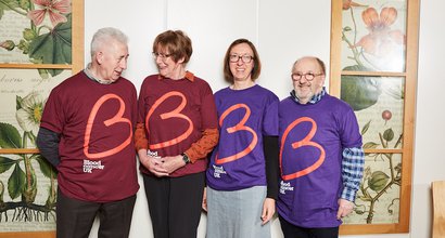 Group of Blood Cancer UK supporters standing side-by-side smiling together wearing Blood Cancer UK branded t-shirts.