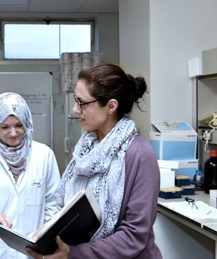 Three researchers looking at a book together in a research lab.