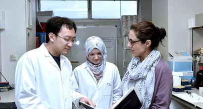 Three researchers looking at a book together in a research lab.