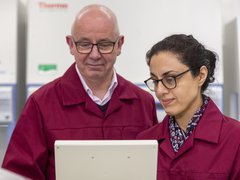 Two Blood Cancer UK Researchers standing side-by-side looking at a screen together.
