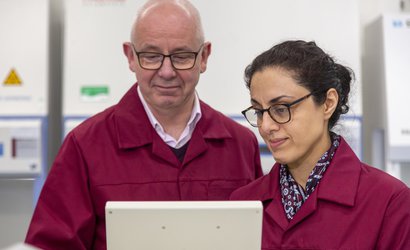 Two Blood Cancer UK Researchers standing side-by-side looking at a screen together.