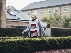 Erica, who has chronic lymphocytic leukaemia (CLL) walking down a path between two bushes.