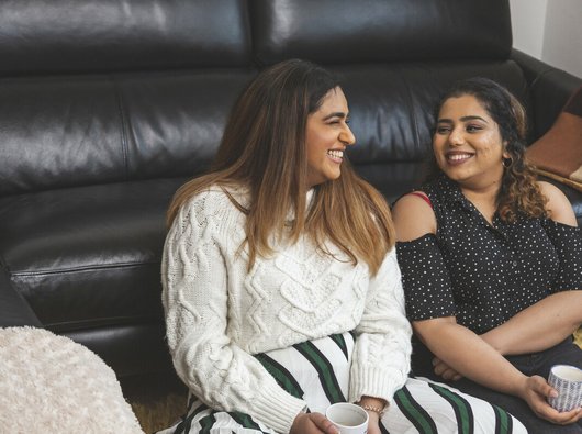 Two friends talking and having a hot drink together.