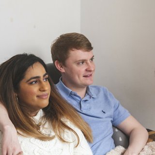 Two friends sitting together with arms round each other.