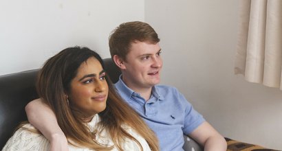 Two friends sitting together with arms round each other.