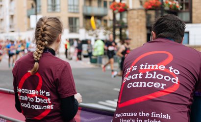 Two people wearing Blood Cancer UK t shirts, standing at a cheer point.