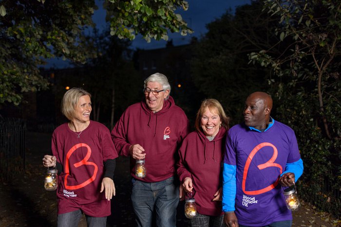 A group of supporters smile and wear their Blood Cancer UK t-shirts as they take part in Walk of Light
