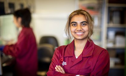 A researcher smiles at the camera, wearing a burgundy Blood Cancer UK jacket