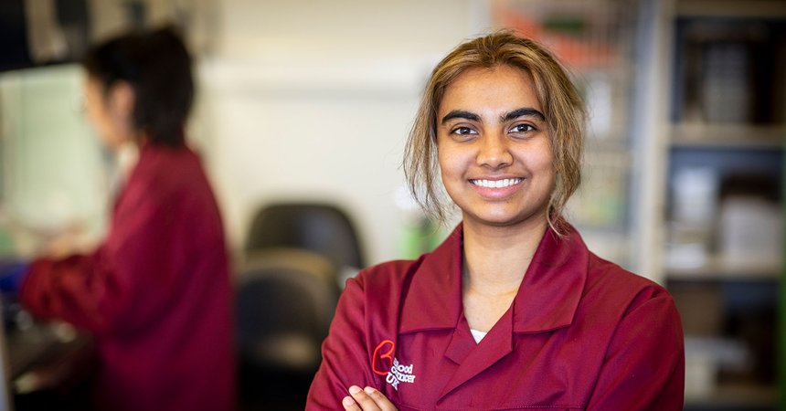 A researcher smiles at the camera, wearing a burgundy Blood Cancer UK jacket