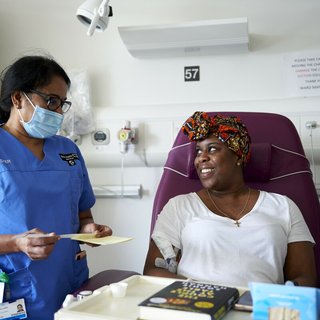 A patient smiles at a health care professional in a hospital room