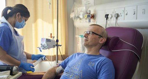 A healthcare professional giving treatment to a man in hospital.