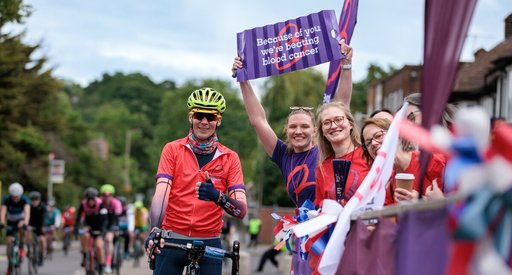 Blood Cancer UK staff members cheering on a cyclist who has just completed a sports events.