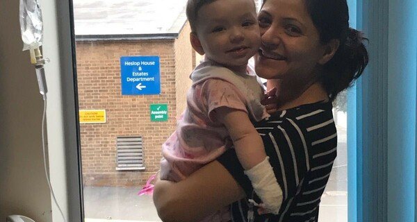 A mother holding her child up in the air and smiling.