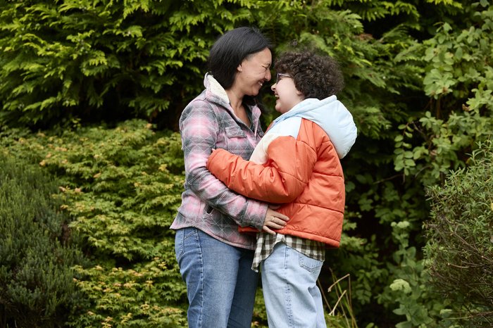 Alyssa and mum, Kiona, outside, facing each other and laughing as they embrace.