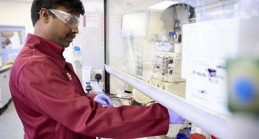 A researcher working in a lab, wearing goggles.