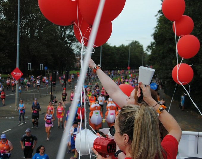 Volunteers on top of double decker bus cheering on runners