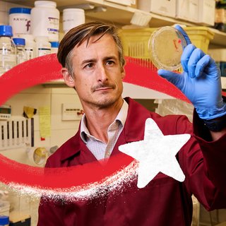 A researcher in a laboratory looks at a petri dish which he is holding up to the light. A red and white Christmas star swirls around him.