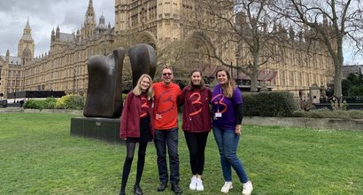 Four people wearing Blood Cancer UK t-shirts, standing outside parliament.