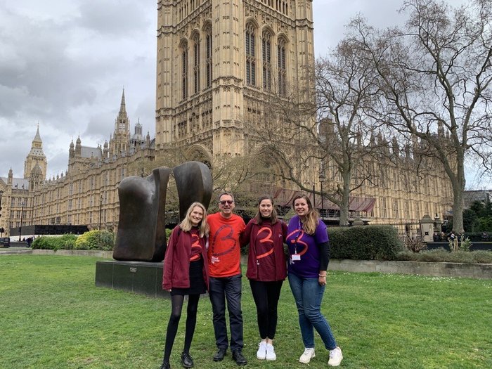 Four people wearing Blood Cancer UK t-shirts, standing outside parliament.