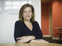 Gemma Peters, former CEO of Blood Cancer UK, sitting with her arms folded at a desk.