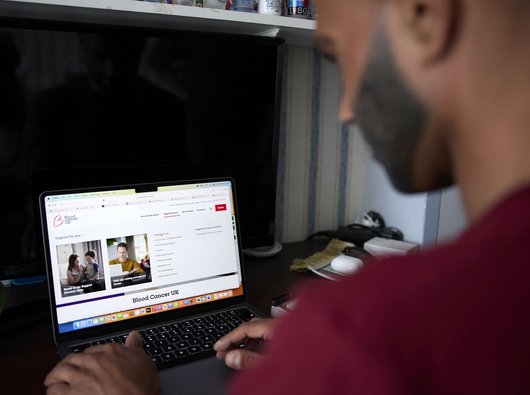 An Asian man looking at blood cancer information on the Blood Cancer UK website.