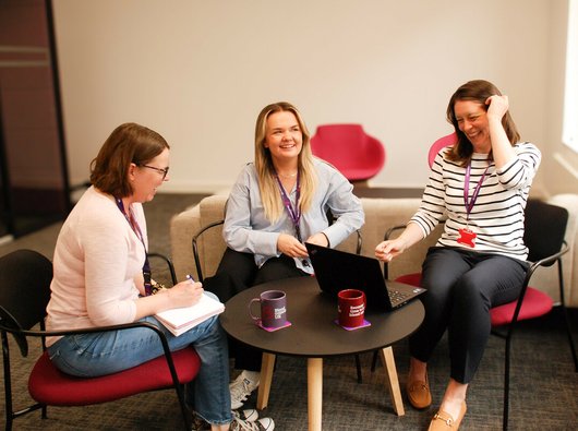 Our support services nurses sitting in the Blood Cancer UK London office, smiling and talking.