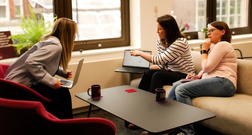 Three Blood Cancer UK members of staff chatting and talking by their computers in the office.