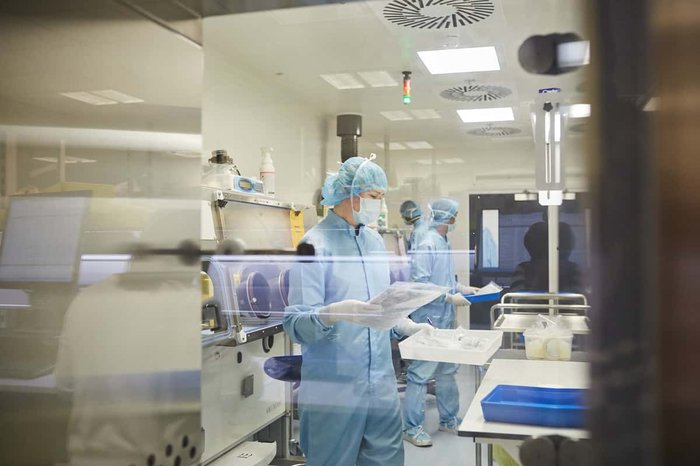 Three researches in full body personal protective equipment conducting tests in a research facility.