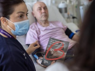 Nurse giving a patient a blood cancer uk flyer