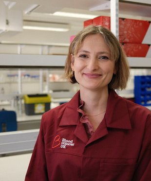 Charlotte Graham, researcher at Kings College London, smiling in her Blood Cancer UK lab coat.