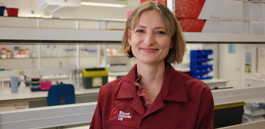 Charlotte Graham, researcher at Kings College London, smiling in her Blood Cancer UK lab coat.