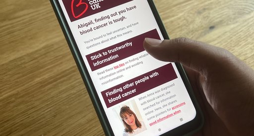 Photo of a hand holding a smart phone, looking at an email that talks about blood cancer information and support.