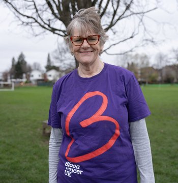 Female wearing purple Blood Cancer UK t shirt smiling to the camera