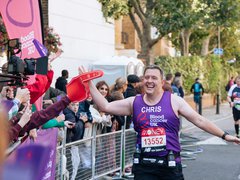 A runner high fives a supporter during a marathon. He wears a Blood Cancer UK vest.