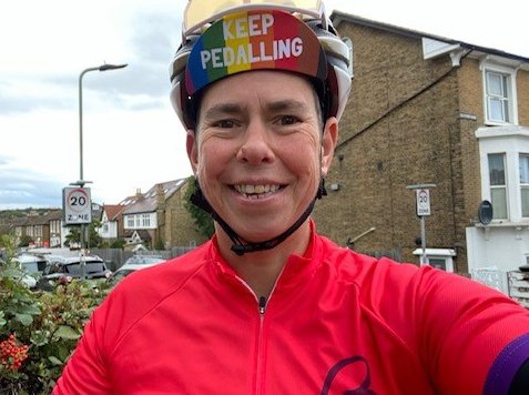 A cyclist smiles at the camera in their cycling gear
