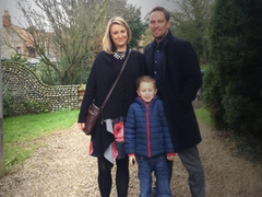 Simon Thomas poses with wife and child outside.
