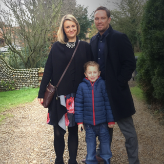 Simon Thomas poses with wife and child outside.