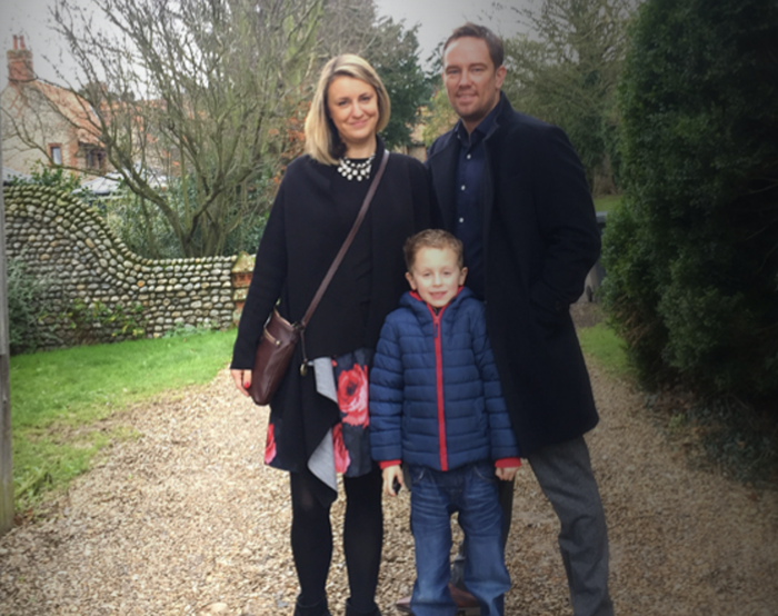 Simon Thomas poses with wife and child outside.