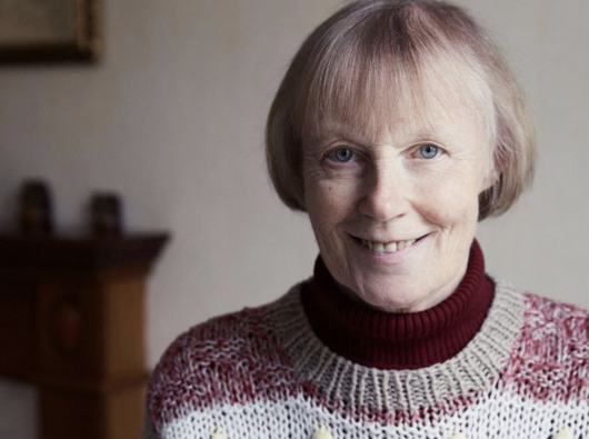 A headshot of Erica, who has chronic lymphocytic leukaemia (CLL), wearing a thick knitted jumper smiling into the camera.