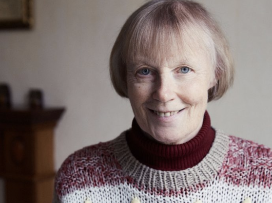 A headshot of Erica, who has chronic lymphocytic leukaemia (CLL), wearing a thick knitted jumper smiling into the camera.