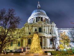 St Paul's Cathedral, London lit up at night with Christmas tree in front.