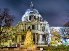 St Paul's Cathedral, London lit up at night with Christmas tree in front.