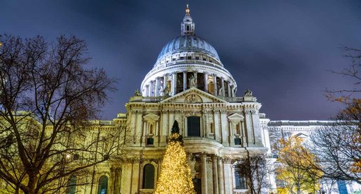 St Paul's Cathedral, London lit up at night with Christmas tree in front.