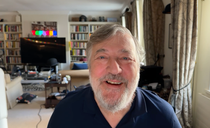 A close up of Stephen Fry at his home, smiling.