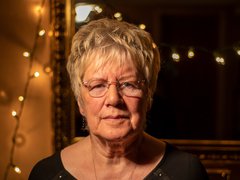 Sylvia Gaunt, daughter of Blood Cancer UK's founders David and Hilda Eastwood, looking into the camera with fairy lights on in the background.