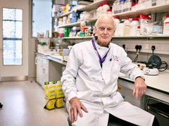 Professor Terry Rabbitts sitting in the lab wearing his lab coat