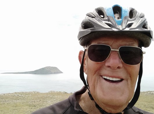 Tony, smiling at the camera in a cycle helmet and sunglasses
